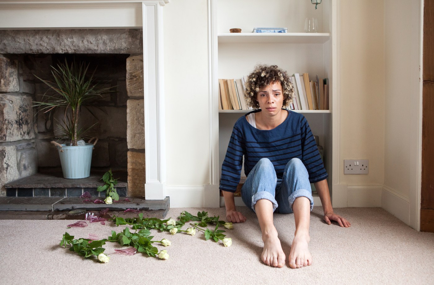 A woman sitting in a living room looking distressed